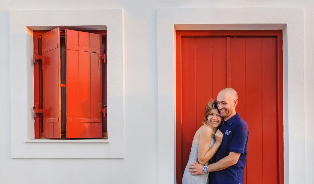 a man and woman hugging in front of red doors