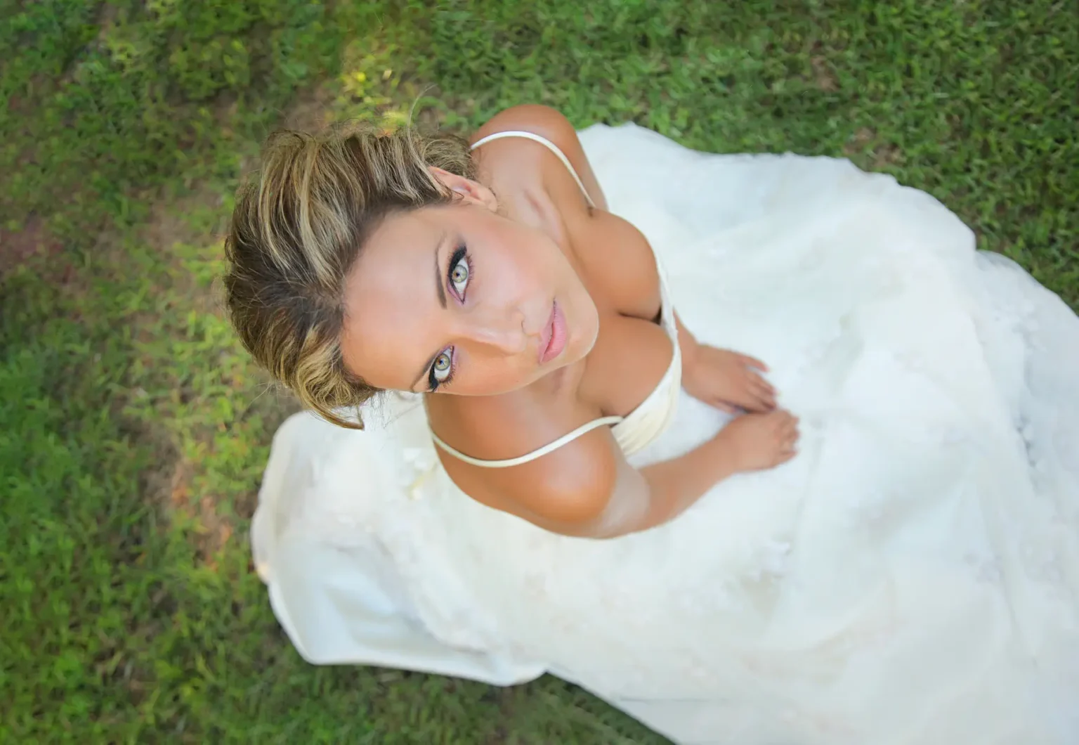 a woman in a white dress sitting on grass