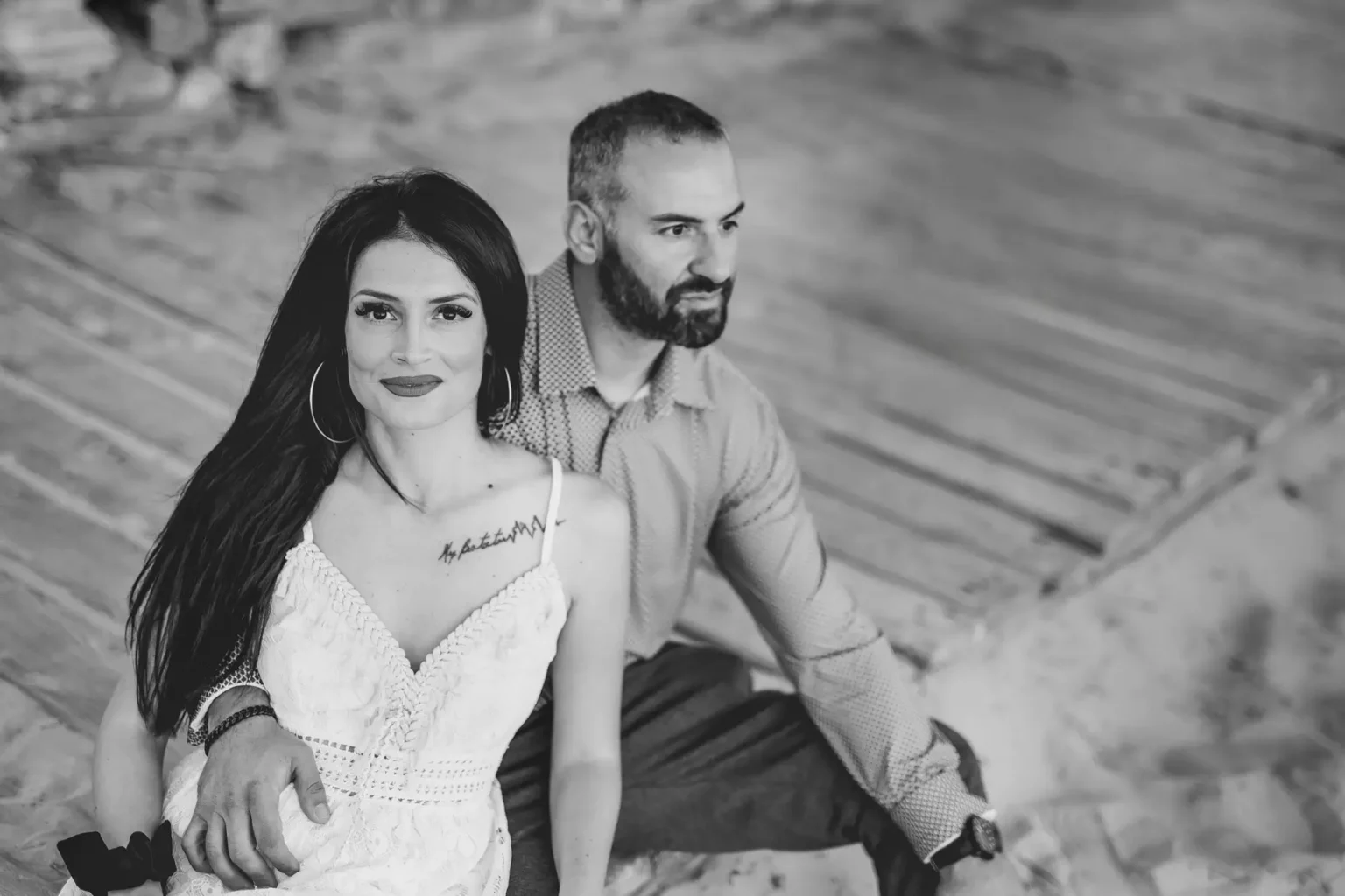 a man and woman sitting on a wood surface