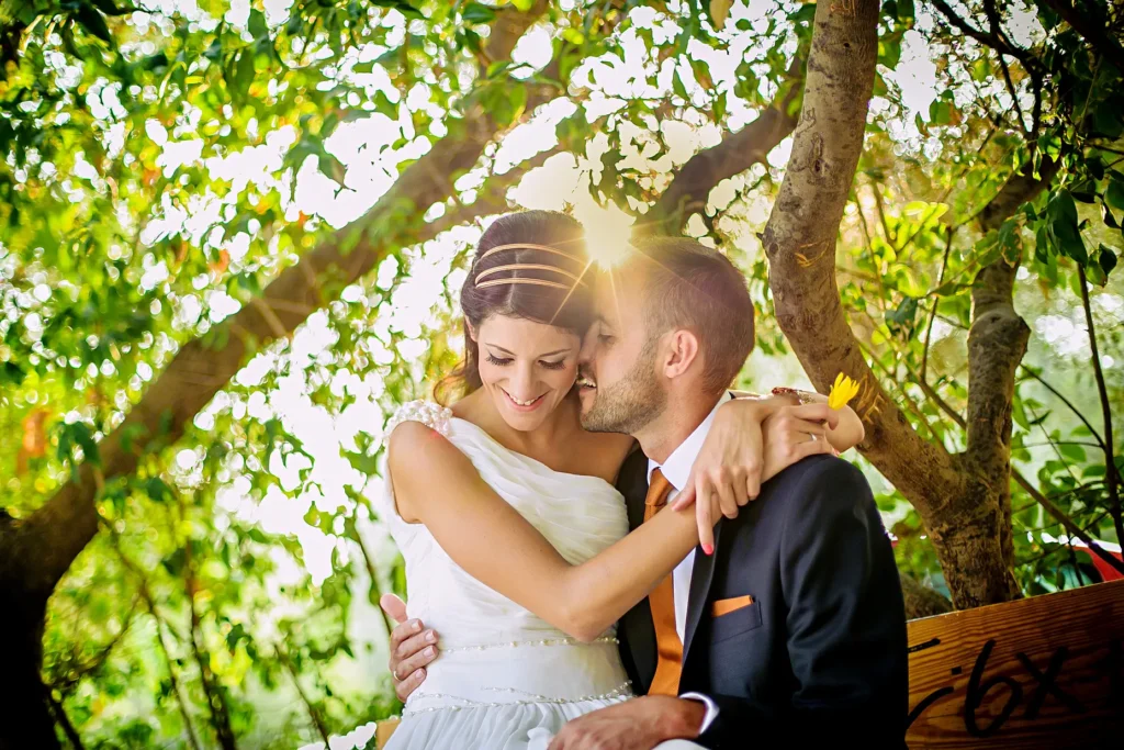 a man and woman in wedding attire kissing under a tree