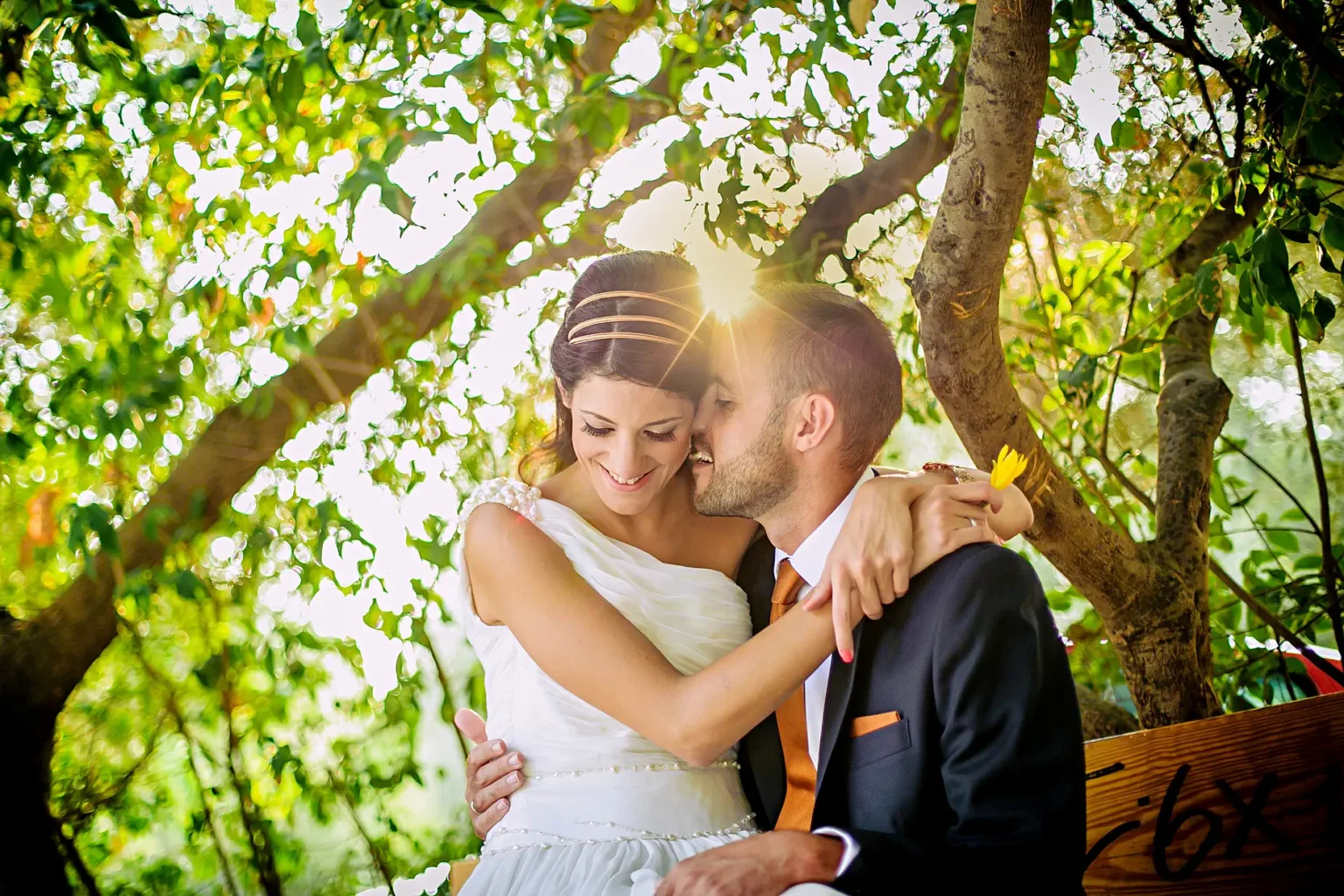 a man and woman in wedding attire kissing under a tree
